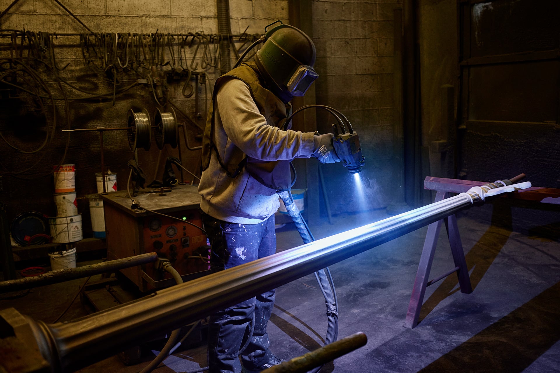 Operator applying a surface treatment to a long metal component.