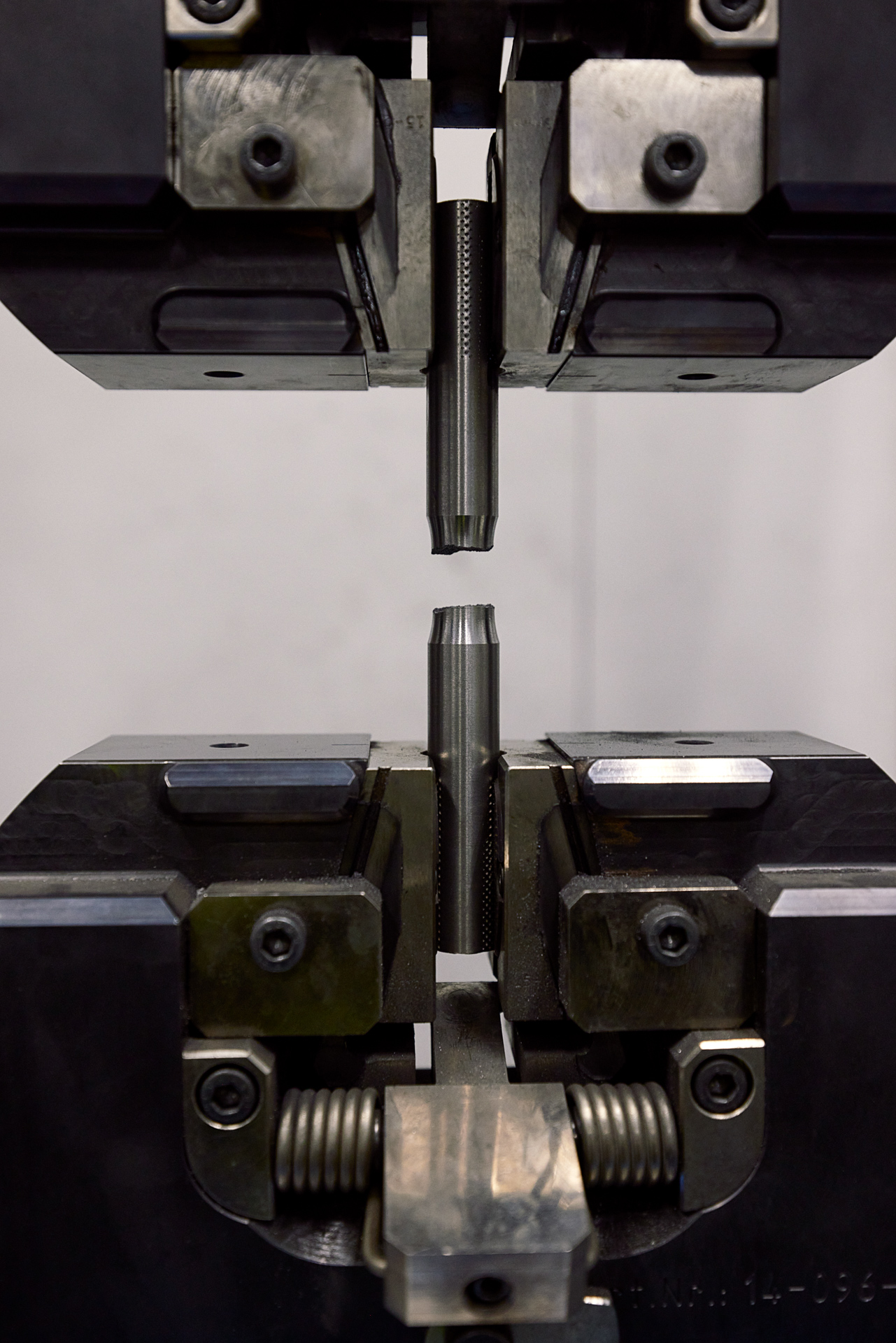 A test specimen held in mechanical testing equipment on Uldall’s inspection page.